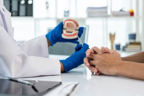 Dental specialist discussing oral surgery and treatment options with a patient during a consultation.
